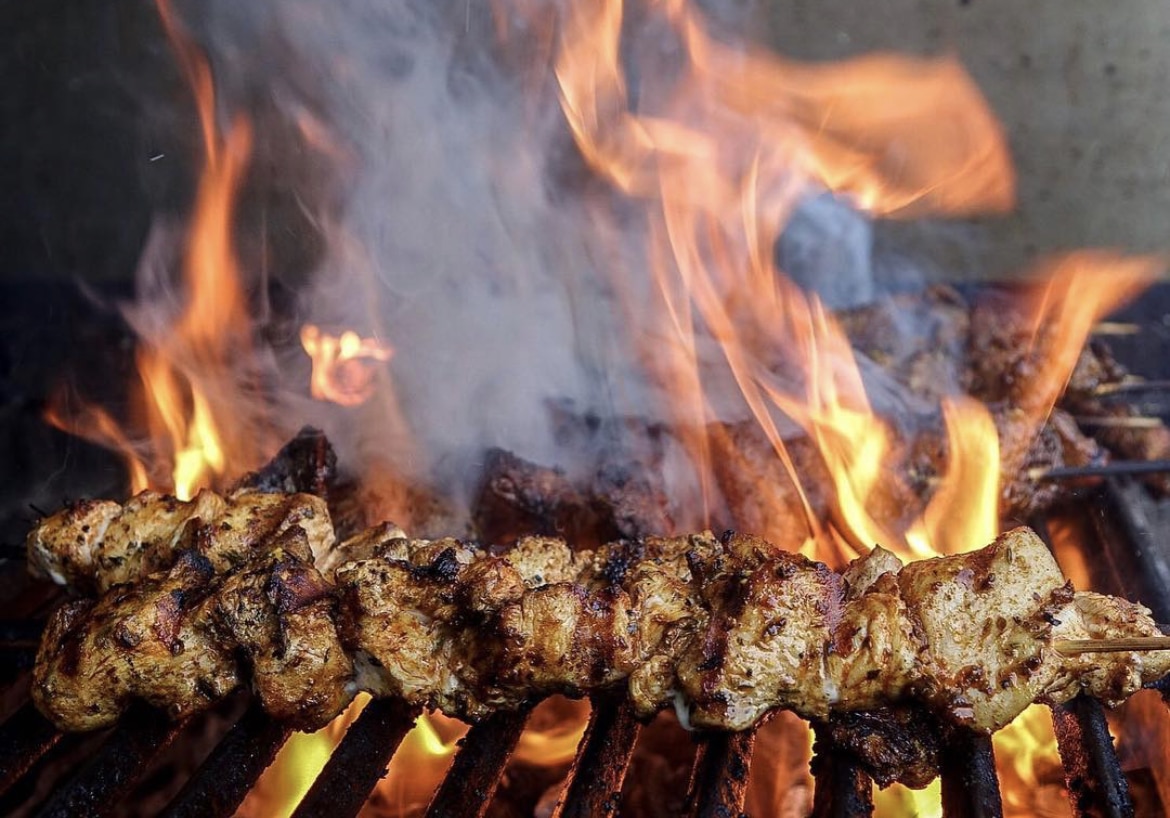 Close up of chicken on the grill and flames in the background